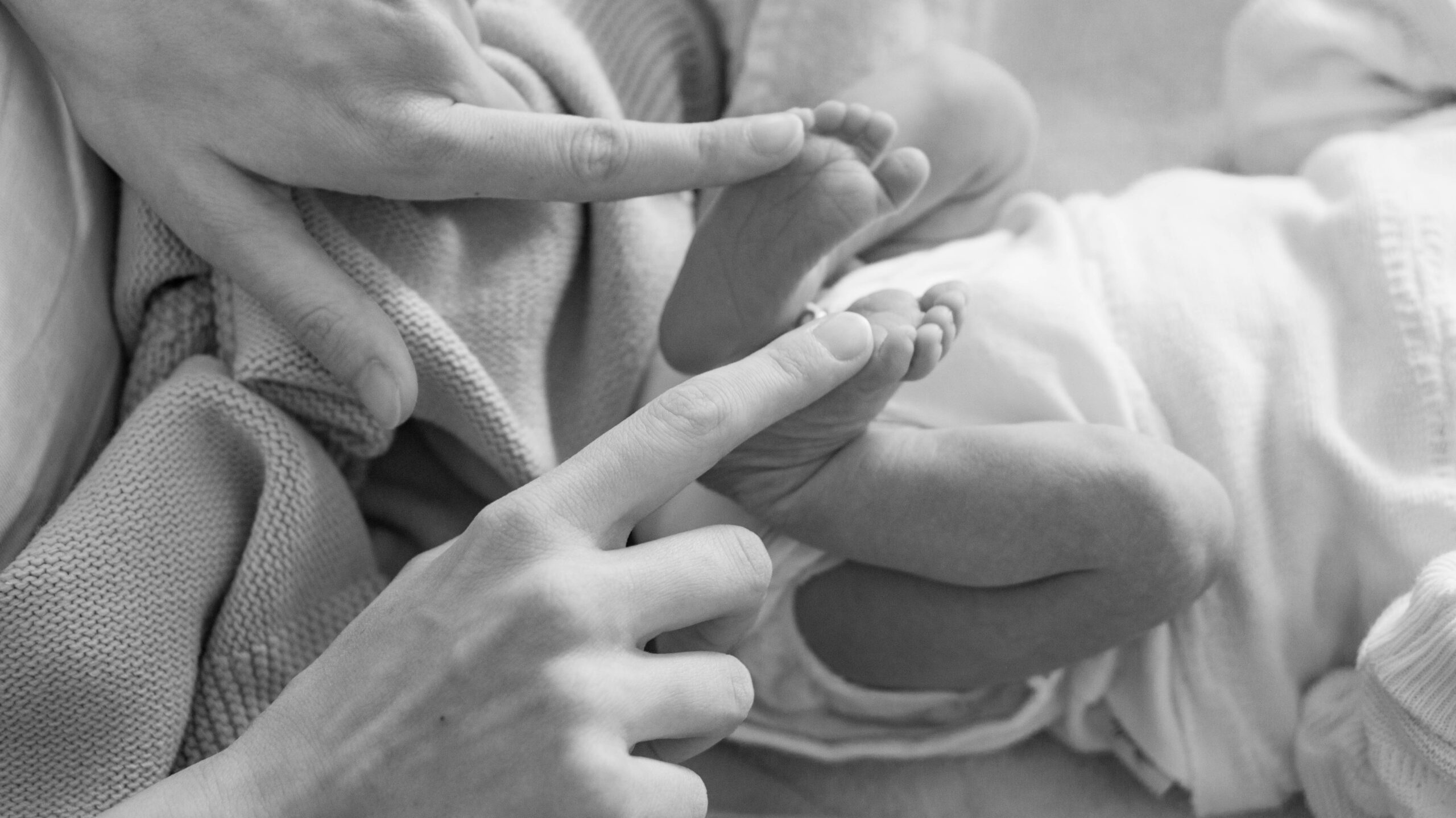 woman's pointer fingers on baby's feet