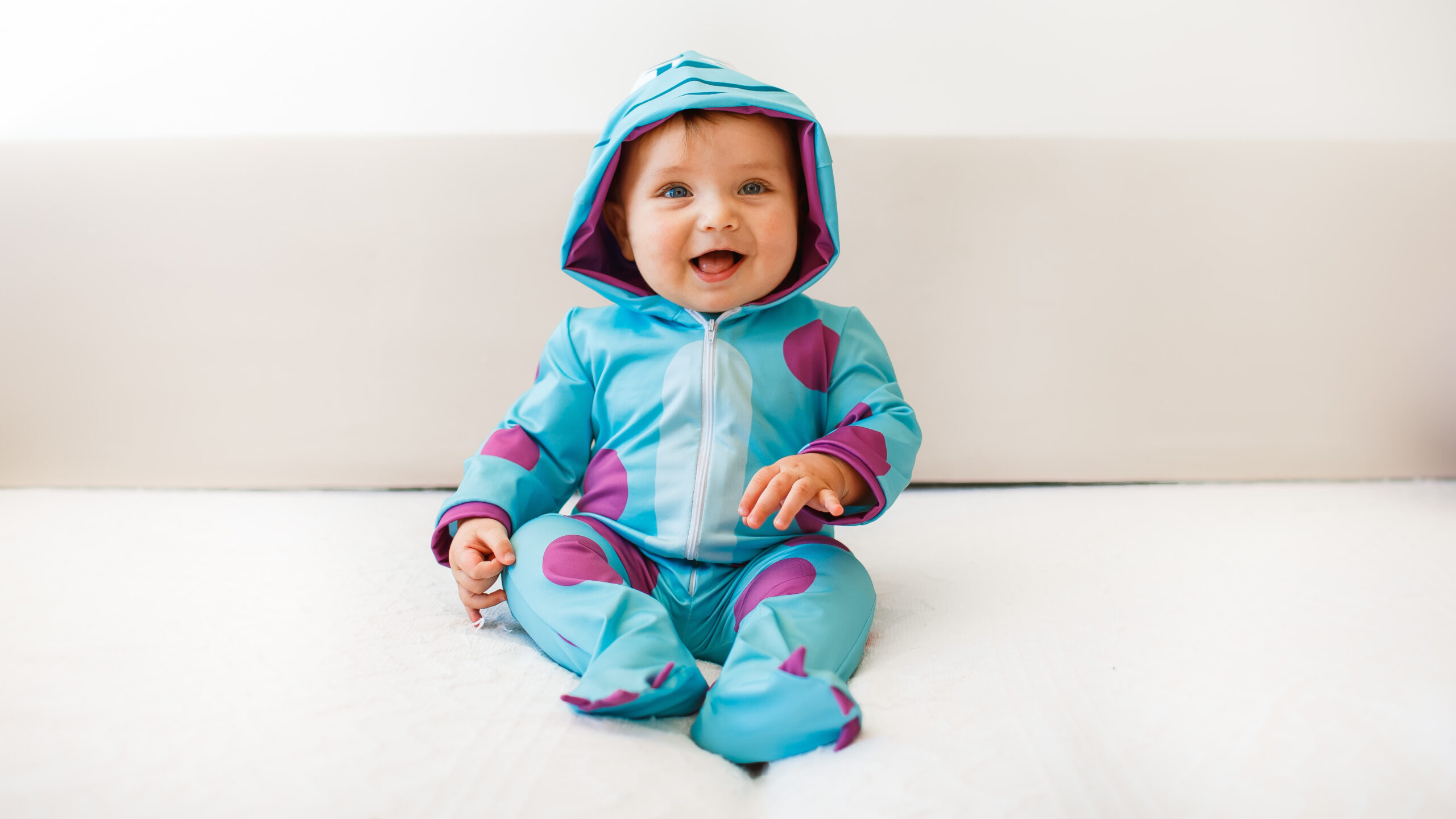 baby in dinosaur onesie sitting and smiling