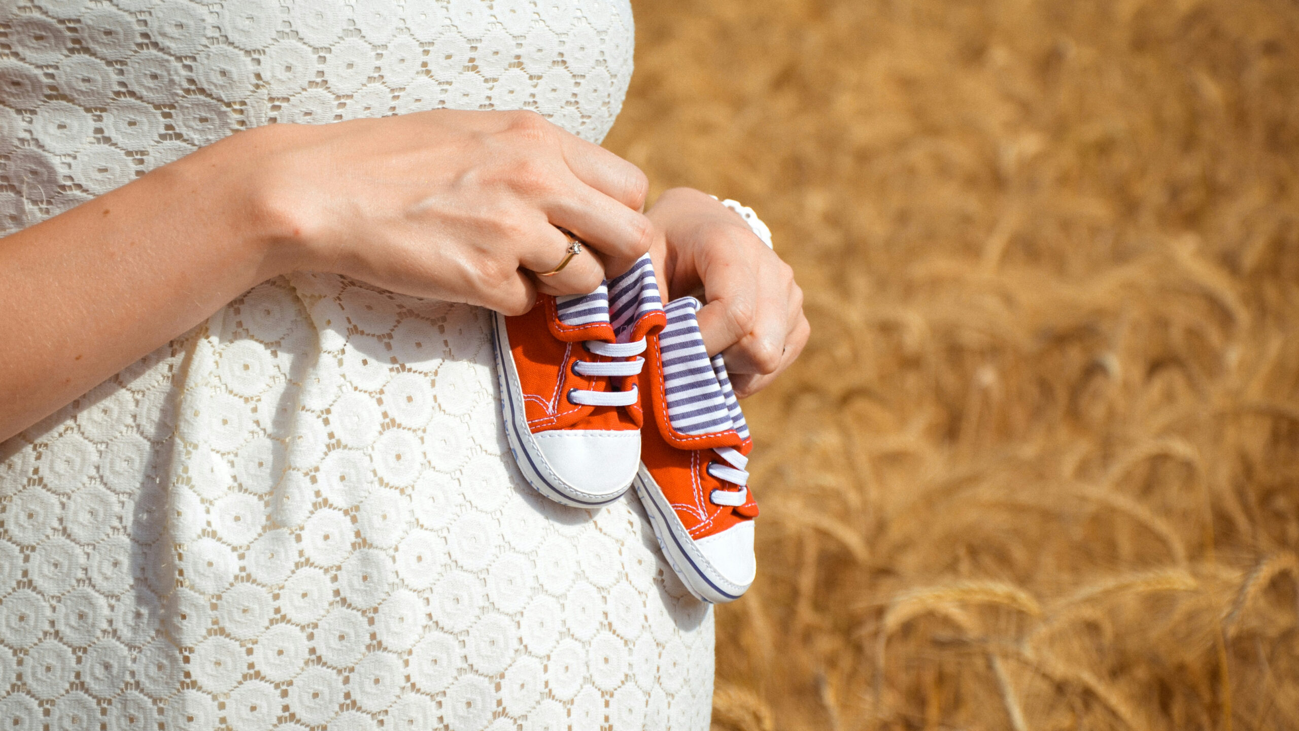 pregnant woman holding baby shoes on belly